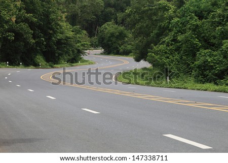 Asphalt road sharp curve along with tropical forest zigzag ahead.