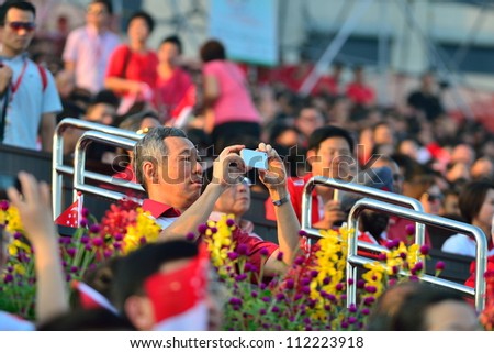 SINGAPORE - AUGUST 09: Singapore Prime Minister Lee Hsien Loong taking photos with his iphone at the VIP gallery during National Day Parade 2012 on August 09, 2012 in Singapore
