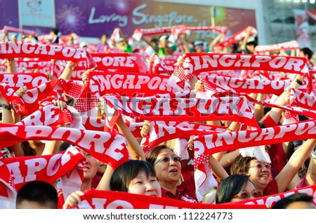 SINGAPORE - AUGUST 09: Enthusiastic audience waving the red Singapore scarves during National Day Parade 2012 on August 09, 2012 in Singapore
