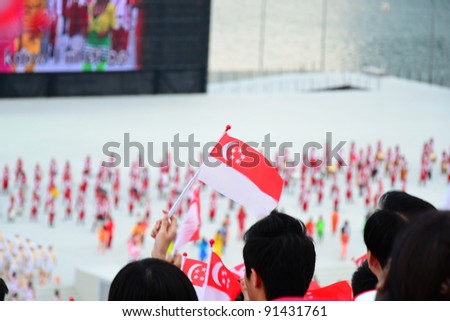 SINGAPORE - AUGUST 9: An enthusiastic spectator waves flag during National Day Parade Singapore 2011 August 09, 2011 in Singapore