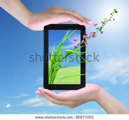 pink flower and fresh grass on tablet PC in women hand