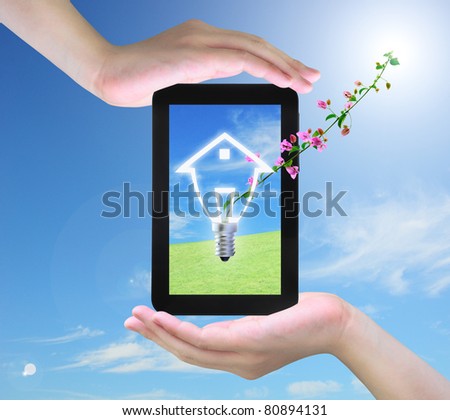 light bulb model of a house and pink flower on tablet PC in women hand