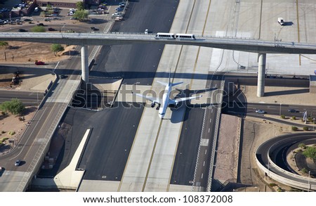 Jet airplane crossing over cars and under a train