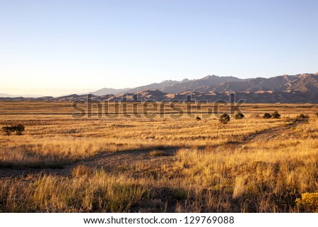 Grasslands at sunset with the Great Colorado Sand Dunes in the distance