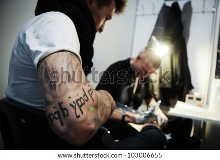 WARSAW - NOV 12: Tattooist makes a tattoo on his client\'s leg during the tattoo, body painting and pierceing show \'Body Art Convention\' on 12th November, 2011 in Warsaw