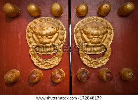 ancient red doors with gilded studs and lion head door knockers in Temple of Heaven, Beijing, China