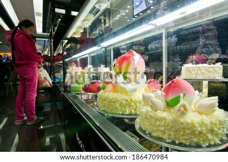BEIJING, CHINA - MARCH 30: Chinese girls looks at cakes in Black Swan Luxury Cake shop on March 30, 2013 in Beijing