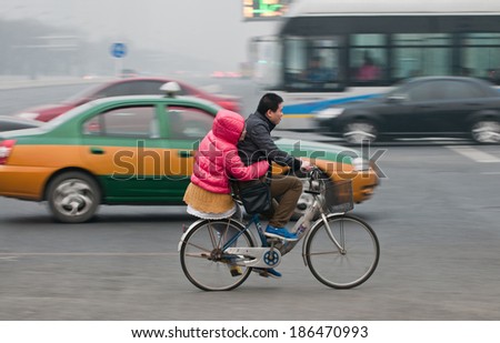 Beijing, China - March 31th, 2013: young man and woman rides bike on a busy street in Dongcheng District on March 31, 2013 in Beijing