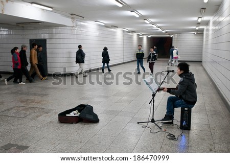 BEIJING, CHINA - MARCH 30: Young Chinese man plays guitar and singing for money in underground passage on March 30, 2013 in Beijing