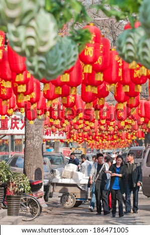 BEIJING, CHINA - APRIL 1: Chinese people walks under red Chinese lanterns in front of restaurants at Dongzhimennei Dajie known as Ghost Street in Dongcheng District on April 1, 2013 in Beijing
