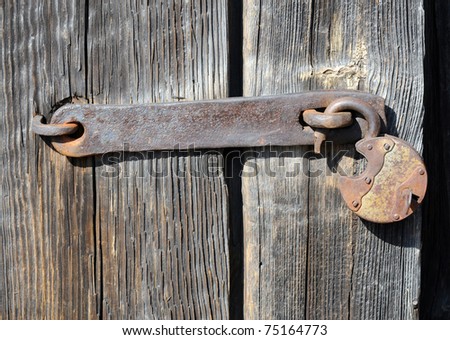 old rusty padlock with small key on a wooden door