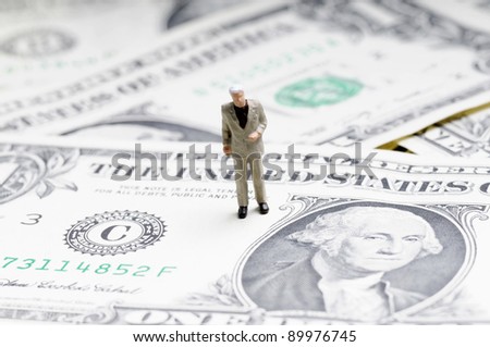 tiny figure of businessman standing on one dollar bill