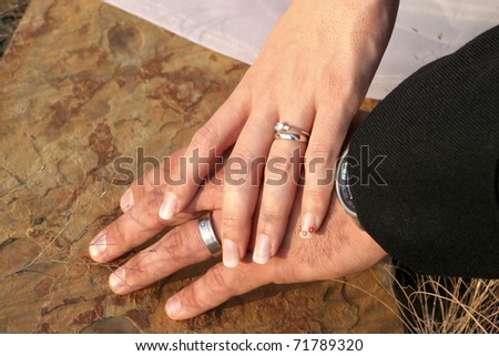 stock photo Couple holding hands with wedding rings against limestone 