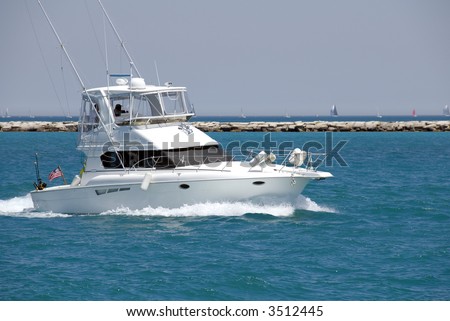 A white sport fishing boat, flying the US Yacht Ensign, heads towards the open sea.