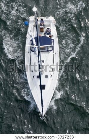 A luxury yacht shot from above as it motors out to sea.