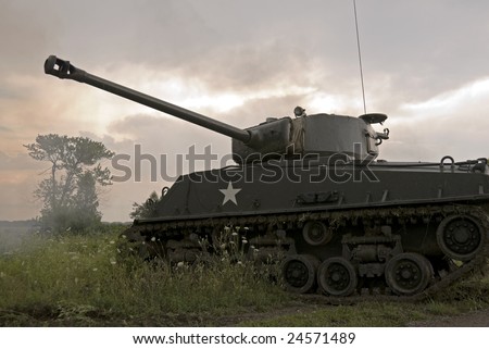 A WWII mark IV Sherman tank moving through hostile terrain during a thunderstorm. Its main gun has just been fired and the smoke is still visible in front of the tree.