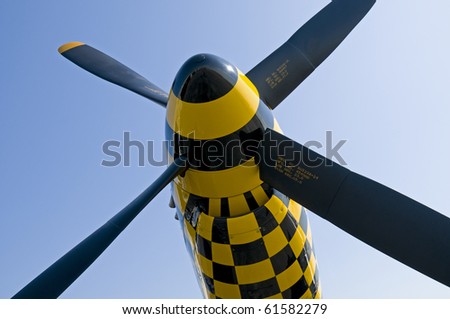 The four-bladed propeller of a North American Aviation P-51 Mustang fighter plane against a cloudless blue sky.