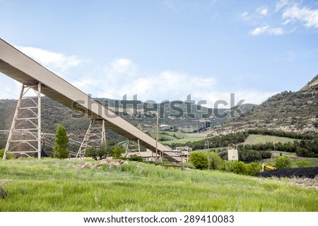 Coal mine infrastructure among beautiful mountains and green grass