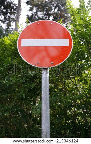 No entry traffic sign in suburb. 	No entrance road sign above green forest background