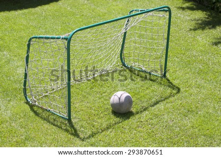 Small football gate with net and ball on the play-field as a background