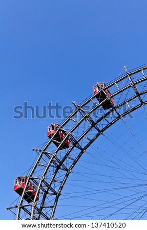 A segment of Vienna\'s ferris wheel with three cabins against the blue sky