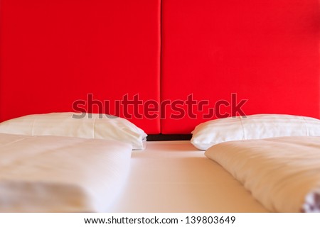 Double bed with separate sheets and a red leather wall