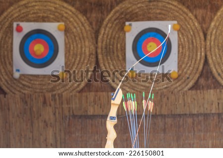 Archery bow and some arrows in front of targets
