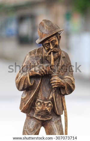 Carved wooden figure of an old full bearded resident from the alps lighting a pipe