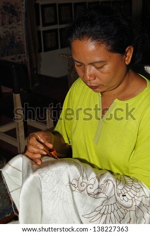 BALI, INDONESIA - MARCH 09, 2013: An unidentified Balinese woman applies dye on a piece of batik, on March 09, 2013 in Bali, Indonesia. Batik-making is an important part of Indonesian culture.