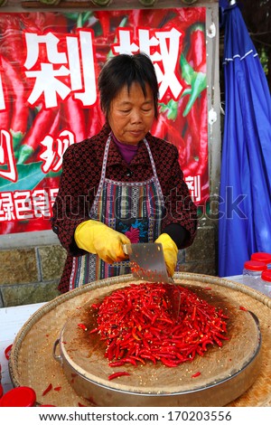 ZHANGJIAJIE, CHINA - OCTOBER 18:  Unidentified woman crushes red pepper  and garlic  by means of two axes, October 18, 2013 in Zhangjiajie National Park, China