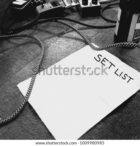 Rock band blank set list on a stage with guitar pedals and cables - Black and White grainy instagram style filtered image