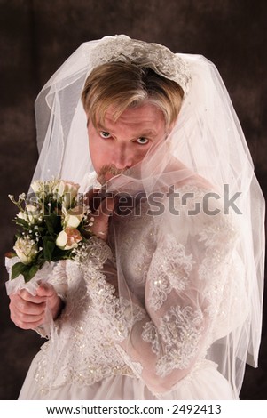 A stock image of a masculine man dressed in a bridal gown. Comical.