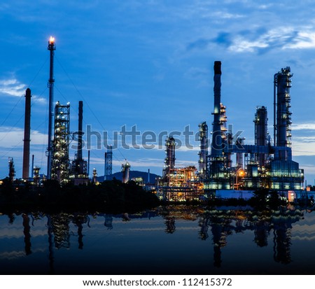 Petrochemical industry on sunset dark blue sky with river shadow.