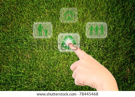 Hand pressing recycle icon on the grass field.