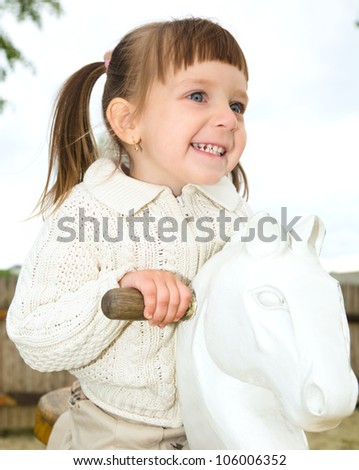 Happy little girl is swinging on see-saw