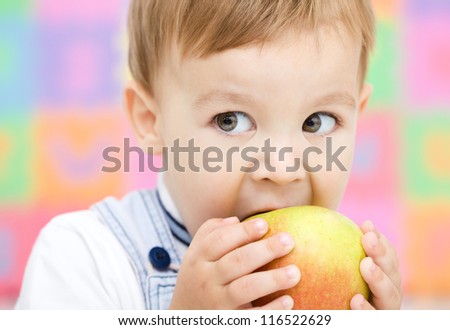 Cute little child is biting red apple and smile, isolated over white