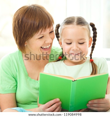 Mother is reading book for her daughter, indoor shoot