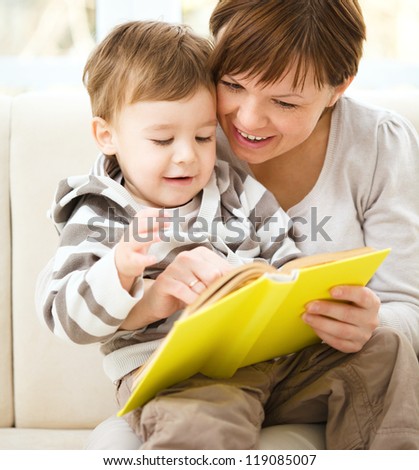 Mother is reading book for her son, indoor shoot