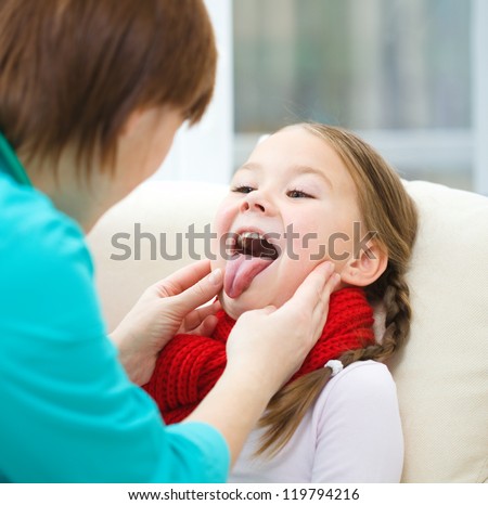 Doctor is examining a little girl who showing tongue, indoor shoot