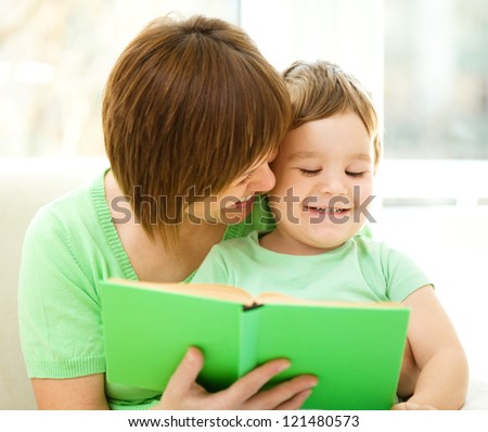 Mother is reading book for her son, indoor shoot