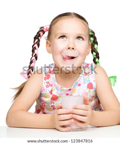 Cute little girl is licking her lips while drinking milk, isolated over white