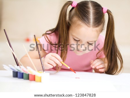 Cute cheerful child play with paints while sitting at table