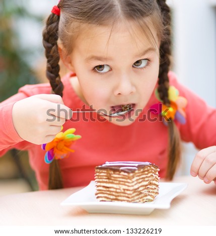 Cute little girl is eating cake in parlor