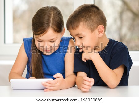 Children are using tablet while sitting at table, isolated over white