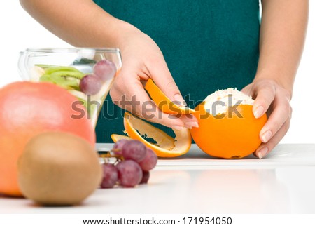 Cook is peeling orange for fruit dessert, closeup shoot, isolated over white