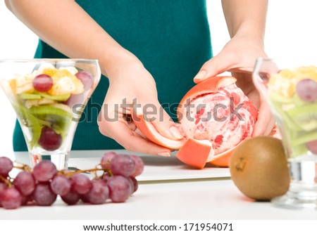 Cook is peeling grapefruit for fruit dessert, closeup shoot, isolated over white