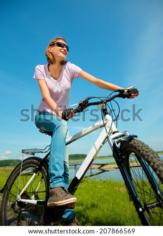 Young happy woman is sitting on her bicycle, outdoor shoot