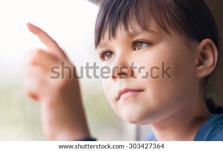 Girl is drawing something on window while sitting in train, closeup shoot