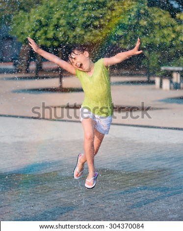 Hot summer in the city - girl is running through fountains