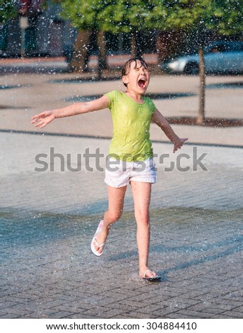 Hot summer in the city - girl is running through fountains